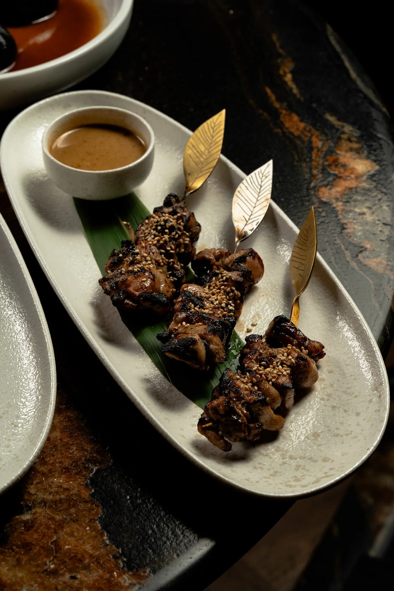 Sesame-glazed skewers served on a dark stone table
